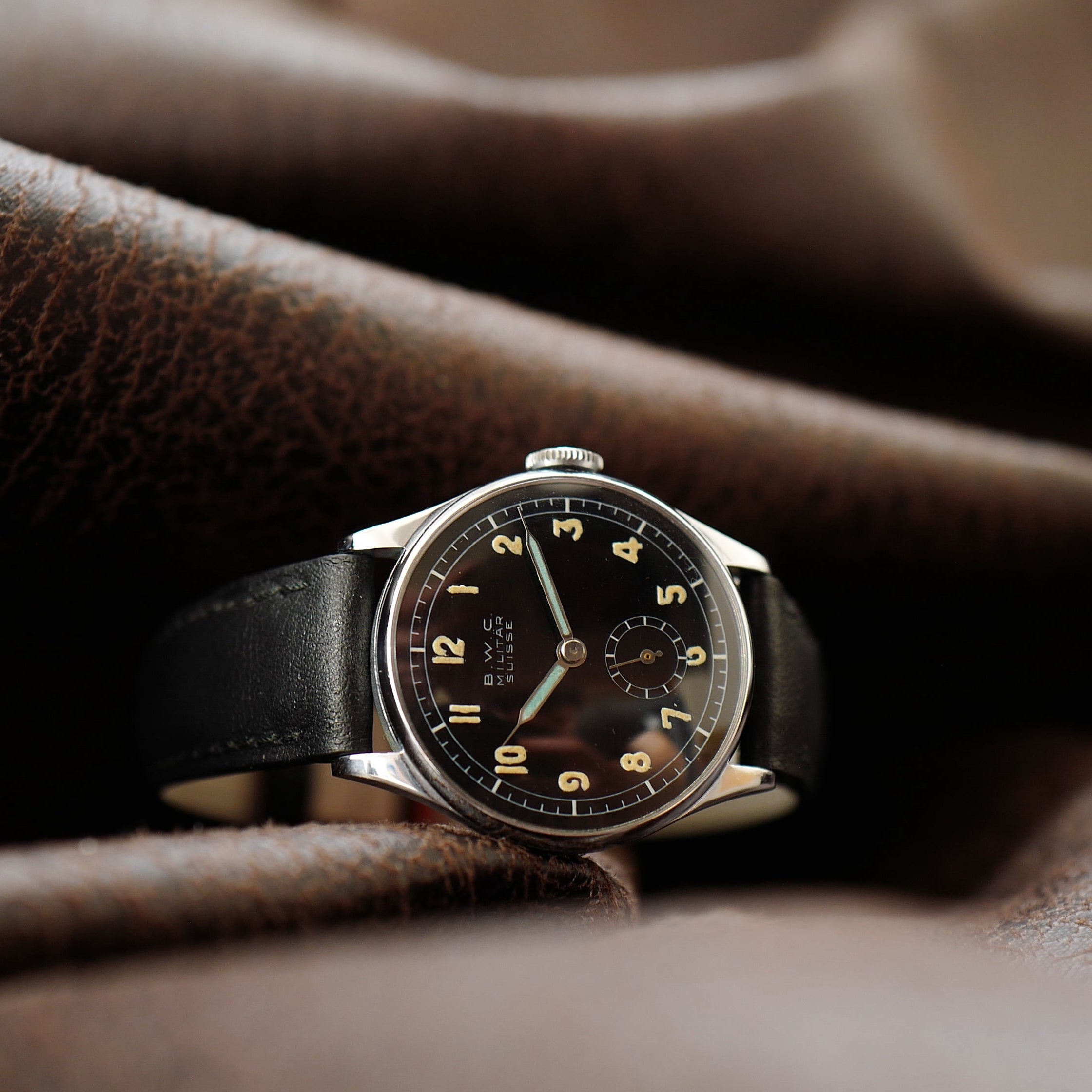 Montre BWC Militar Suisse WWII, modèle Buttes, en état N.O.S, avec cadran noir et bracelet en cuir, vue de face.