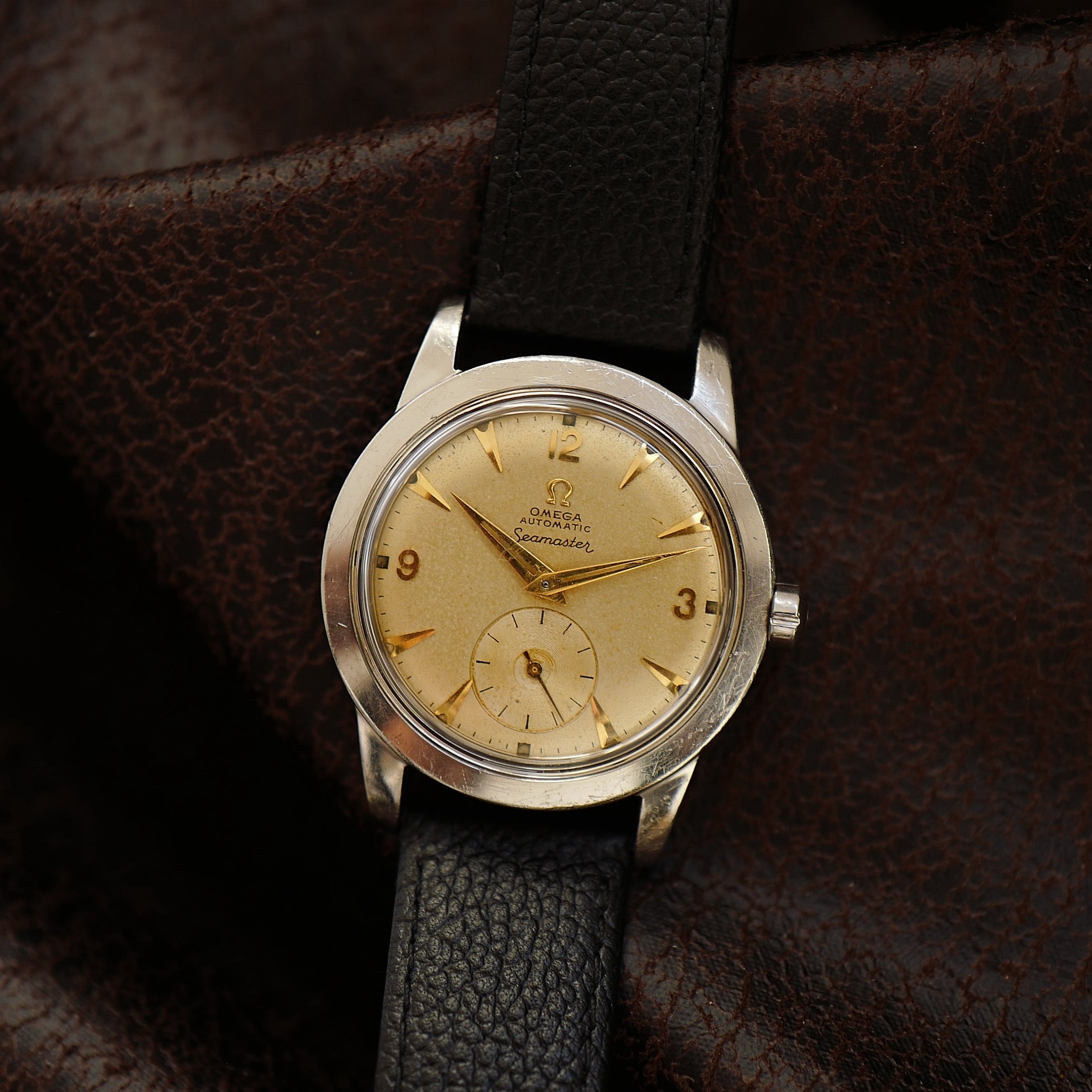 Montre Omega Seamaster avec cadran sable et petite seconde, vintage des années 1950, mouvement mécanique visible.