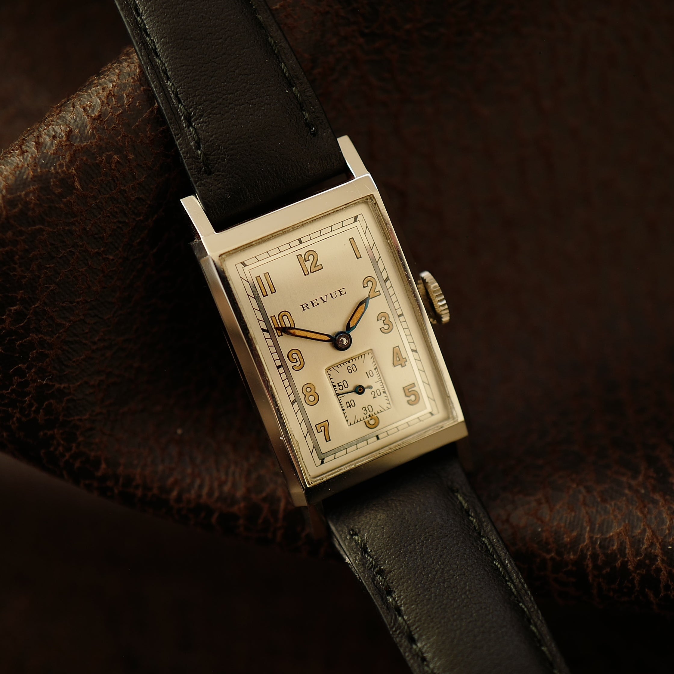 Montre Revue Type Tank Art Déco WWII N.O.S avec cadran noir, boîtier en acier et bracelet en cuir, style vintage.