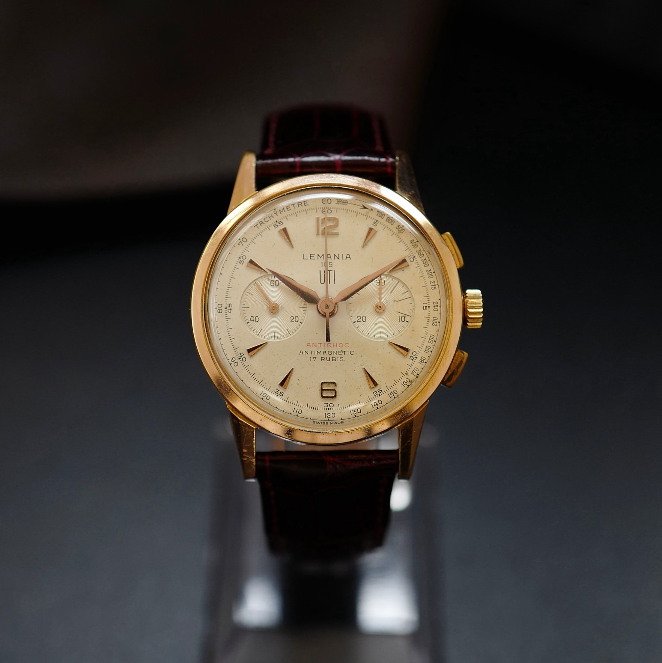 Montre chronographe Lemania Uti 105 plaquée or rose avec cadran beige et bracelet en cuir bordeaux. 