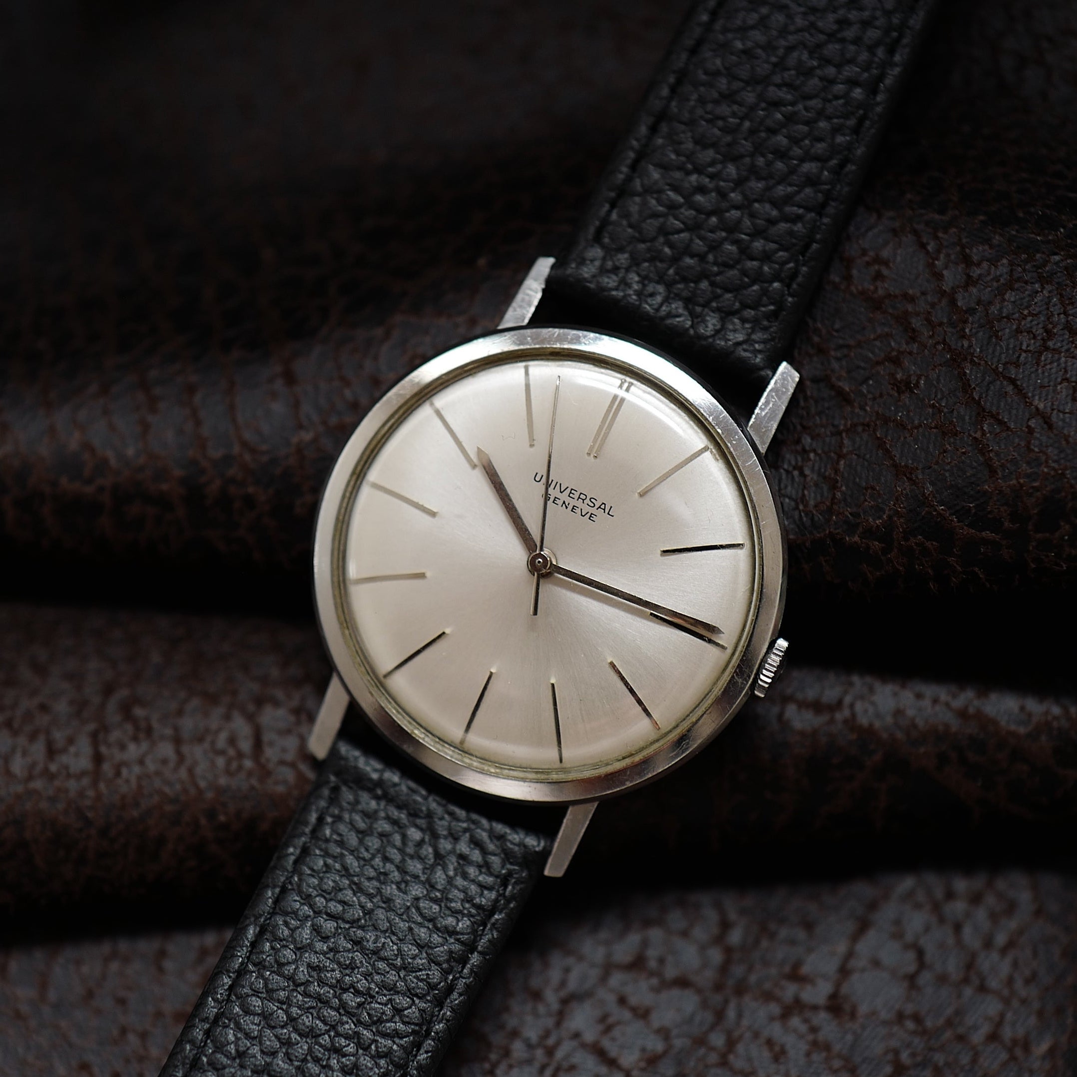 Montre Universal Genève à boîtier fin en argent avec cadran des années 1960, affichage classique et bracelet en cuir.